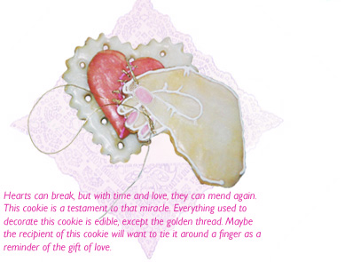 Photograph of a cookie that is made in the image of a hand  mending a broken heart with a gold needle and thread.